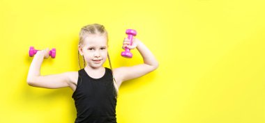 Tema spor ve sağlık. Gülümseme ile sarı arka plan üzerinde poz pigtails kız güzel çocuk. küçük atlet holding pembe dambıl. Banner reklam, metin kopya alanı alan için
