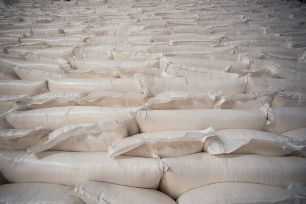 Industria temática y economía, existencias en stock.A gran cantidad de bolsas de tela blanca de cerca con productos sueltos apilados en pilas en el interior de la producción. Angar para almacenar el producto terminado en el paquete . —  Fotos de Stock