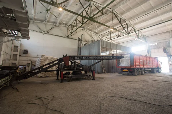 Industria temática y economía, existencias en stock.A una gran cantidad de bolsas de tela blanca con productos sueltos apilados en pilas en el interior de la producción. Cargador en un almacén para transportar bolsas en un camión . — Foto de Stock