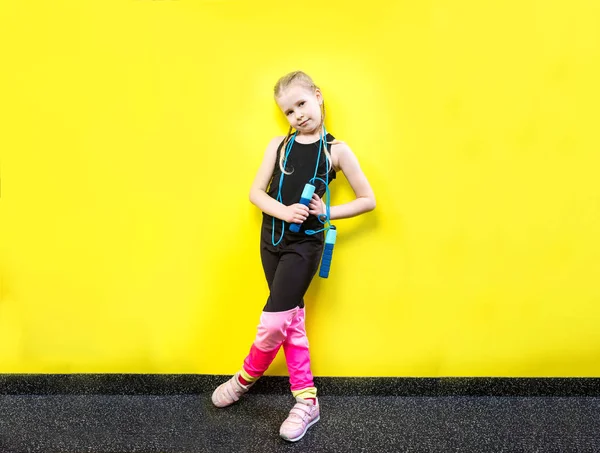 Thema sport en gezondheid. Mooie Kaukasische kind meisje met pigtails gele achtergrond met glimlach te poseren. weinig atleet houdt sport touw in handen. Banner reclame, ruimte voor tekst kopiëren ruimte leeg — Stockfoto