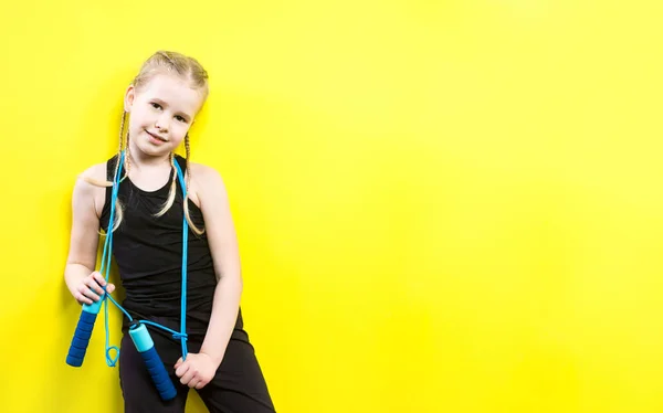 Thema sport en gezondheid. Mooie Kaukasische kind meisje met pigtails gele achtergrond met glimlach te poseren. weinig atleet houdt sport touw in handen. Banner reclame, ruimte voor tekst kopiëren ruimte leeg — Stockfoto