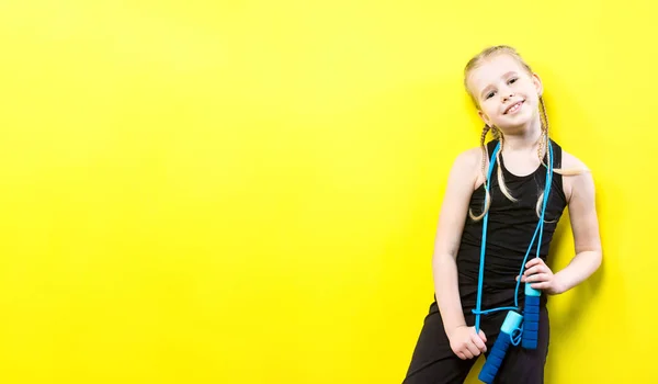 Thema sport en gezondheid. Mooie Kaukasische kind meisje met pigtails gele achtergrond met glimlach te poseren. weinig atleet houdt sport touw in handen. Banner reclame, ruimte voor tekst kopiëren ruimte leeg — Stockfoto