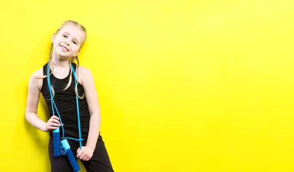 Thema sport en gezondheid. Mooie Kaukasische kind meisje met pigtails gele achtergrond met glimlach te poseren. weinig atleet houdt sport touw in handen. Banner reclame, ruimte voor tekst kopiëren ruimte leeg — Stockfoto