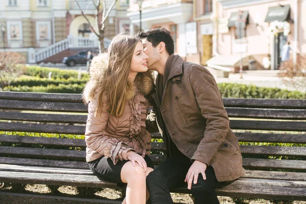 Jong multiraciale koppel, mannelijke en vrouwelijke heteroseksuele studenten verliefd. Een datum in een stadspark op een houten bankje. Jonge brunette man met donkere huid en een Kaukasische vrouw in een omhelzing op een zonnige dag — Stockfoto