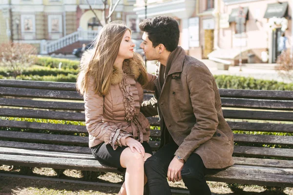 Jong multiraciale koppel, mannelijke en vrouwelijke heteroseksuele studenten verliefd. Een datum in een stadspark op een houten bankje. Jonge brunette man met donkere huid en een Kaukasische vrouw in een omhelzing op een zonnige dag — Stockfoto