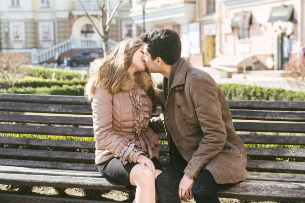 Jeune couple multiracial, étudiants hétérosexuels masculins et féminins amoureux. Un rendez-vous dans un parc municipal sur un banc en bois. Jeune homme brune à la peau foncée et une femme caucasienne dans une étreinte par une journée ensoleillée — Photo