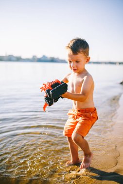 Konu inşaat ve ağır sanayi. Soyutlama çocuk çocuk yaz oyuncak kırmızı traktör modeli nehirde, bir kova ile tarak makine yakınındaki kum oynamak