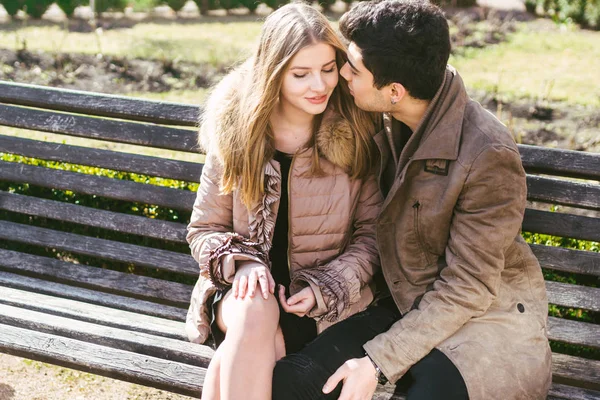 Jeune couple multiracial, étudiants hétérosexuels masculins et féminins amoureux. Un rendez-vous dans un parc municipal sur un banc en bois. Jeune homme brune à la peau foncée et une femme caucasienne dans une étreinte par une journée ensoleillée — Photo