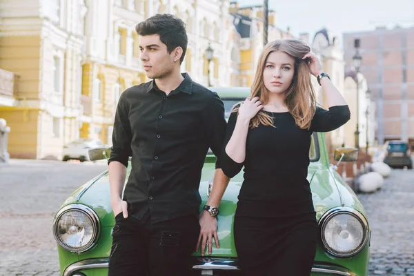 Jovem casal multirracial, homens e mulheres amantes heterossexuais pessoas estudantes. Belos modelos posando de pé perto de um carro retro na cidade. Vestido com roupas pretas — Fotografia de Stock