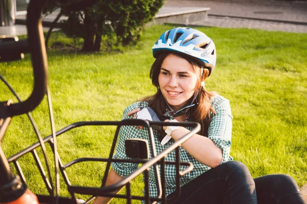 Ciclista donna in abbigliamento ciclistico professionale e casco seduto vicino alla bicicletta, godendo del sole. Rilassati riposandoti. Stile di vita sano — Foto Stock