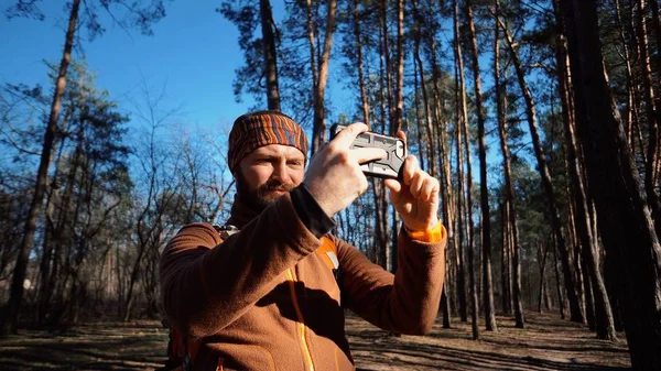 Turystyki pieszej turystyka lasu i technologii. Człowiek kaukaski mężczyzna broda podróżnik używa telefonu ręcznie zrobić zdjęcie wideo z plecaka aktywny styl życia przygoda podróż Las turystyka wypoczynek zewnątrz — Zdjęcie stockowe