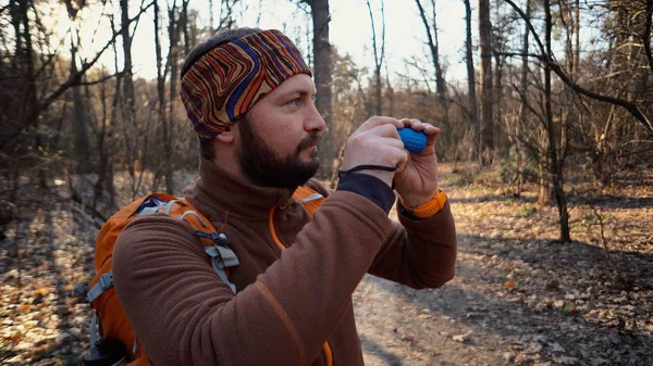 Tourist traveler tourist Caucasian man with a beard and a backpack looking through the shameful pipe on the nature landscape in the forest. A tourist looks at the wildlife in the telescope — Stock Photo, Image