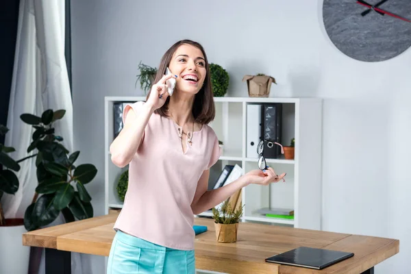 Mujer de negocios hablando por teléfono. Joven hermosa mujer caucásica mano llamada de teléfono inteligente. Hombre de negocios está cerca del escritorio en sus gafas de mano emoción sonrisa felicidad y alegría — Foto de Stock