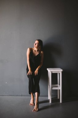 kadın yalnızlık sosyal teması ağrı acı olduğunu. Erkek aile içi şiddetin abastrasyonu. Siyah kıyafetler genç güzel kafkas kadın, garip poz, beyaz sandalye büyük karanlık oda. Korku ve umutsuzluk