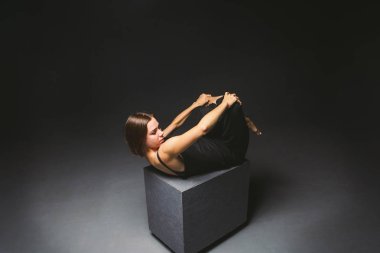 Sosyal tema. siyah küp üzerinde poz elbise garip poz genç kafkas kadın, karanlık arka plan, ağrı sembolize, acı, yardım isteyen, kötü bir toplumun korunması. Modern sanat, soyutlama