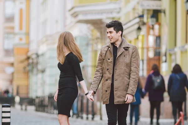 Stedelijke moderne jonge liefde paar wandelen romantisch praten praten, handen vasthouden op een datum. Jonge multiculturele Turkse brunette en Kaukasische paar op oude Europese straat. Herfst lente weer — Stockfoto