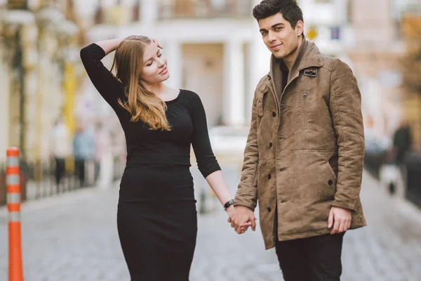 Городская современная молодая влюбленная пара, гуляющая романтично разговаривающая, держащаяся за руки на свидании. Молодая многонациональная турецкая брюнетка и кавказская пара на старой европейской улице. Осенняя весна — стоковое фото
