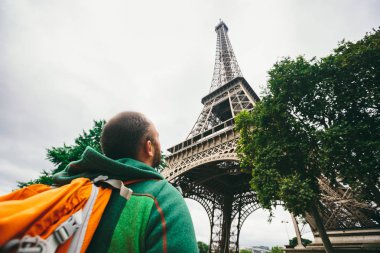Bulutlu havalarda ana cazibe Paris Eyfel Kulesi'nin üst yukarı ve aşağı bakarak bir sırt çantası ile Kafkas erkek turist