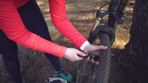 Ung kaukasisk kvinna idrottsman turist cyklist använder ett handverktyg, en cykelpump för att blåsa luft i ett däck hjul mountainbike. Uppdelning och snabb reparation av en cykel på landsbygden utanför — Stockvideo