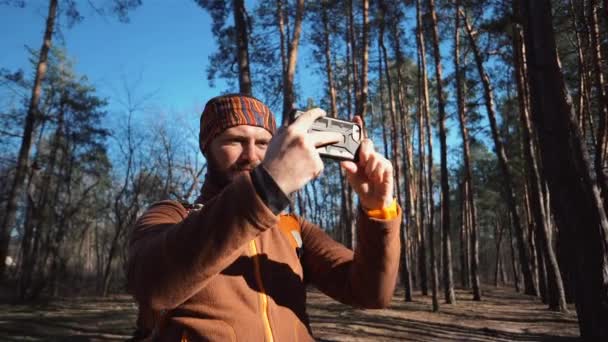 Theme tourism hiking forest and technology. Man Caucasian male beard traveler uses hand phone make photo video with backpack active outdoor travel lifestyle adventure concept active leisure forest — Stock Video