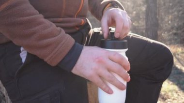 Genç yorgun Kafkas adam yürüyüşler, geziler, tatiller, tatil, açık yaşam tarzı özgürlük kavramı sırasında bir doğa ormanında bir ağaç üzerinde oturan ve içme suyu bir sırt çantası ile bir dinlenme molası taşır