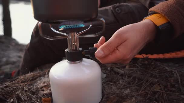 Hands caucasian male traveler, tourist sits in the forest near the lake camping. Uses inventory for cooking. A hand lighter set fire to a torch with a gas balloon — Stock Video