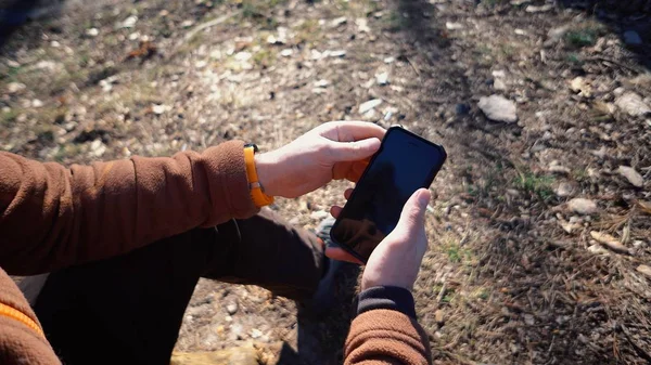 Thema toerisme en technologie. Jonge Kaukasische man wandelen toerist in pine forest maakt gebruik van technologie, hand houden mobiele telefoon om het scherm te raken. GPS applicatie oriëntatie — Stockfoto