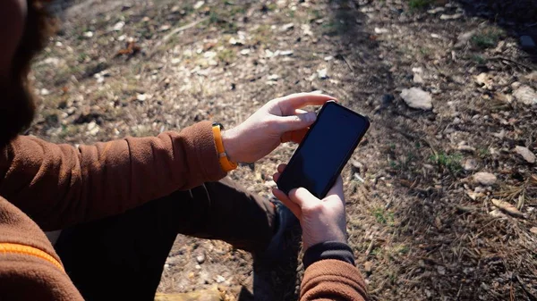 Thema toerisme en technologie. Jonge Kaukasische man wandelen toerist in pine forest maakt gebruik van technologie, hand houden mobiele telefoon om het scherm te raken. GPS applicatie oriëntatie — Stockfoto