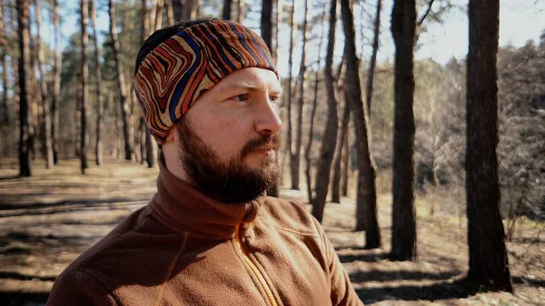 Active male sporty guy portrait hiking outdoors. Young male tourist with a beard and bandage, kerchief on his head wearing a backpack outdoors Caucasian