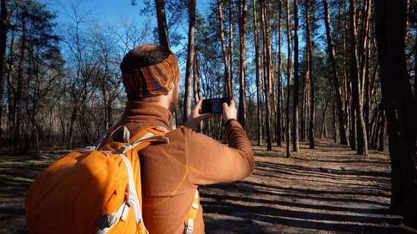 Thema toerisme wandelen bos en technologie. Man Kaukasische mannelijke baard reiziger maakt gebruik van de handtelefoon maken foto video met rugzak actieve outdoor reizen Lifestyle Adventure concept actieve Leisure forest — Stockfoto