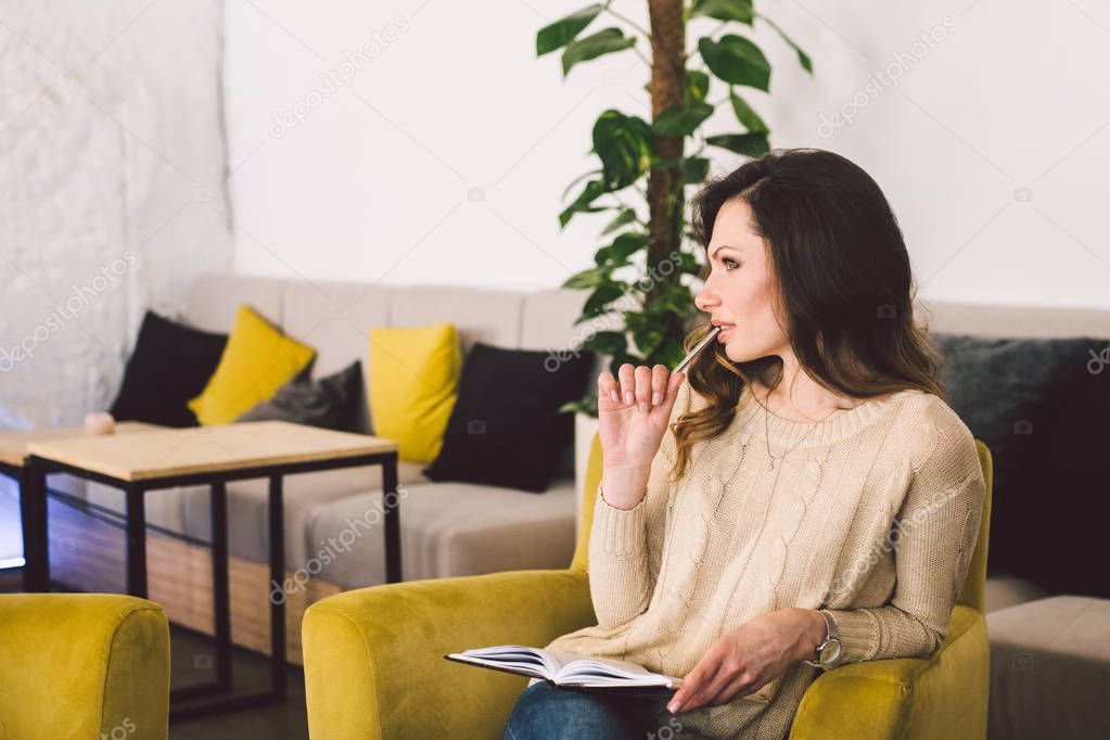 Young Caucasian woman thinking and writing something on a notebook in cafe