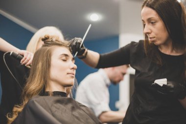 Kaş boyama işi. Usta, güzel bir kıza kına ile kaşlarını boyuyor, bir güzellik uzmanının salonunda fırçayla boya yapıyor. Kaş mimarisi