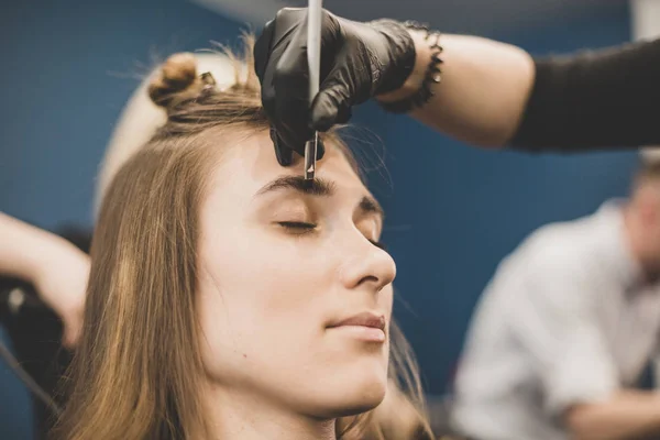 Wenkbrauwverven. De meester schildert wenkbrauwen met henna aan een mooi meisje, schildert met een borstel in de salon van een schoonheidsspecialiste. Brow architectuur — Stockfoto