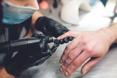 Erkek manikür. Manikür makinesi ile insan için profesyonel manikür. Güzellik salonunda manikür yaptıran bir adam. Beautician master budama ve cuticles kaldırır
