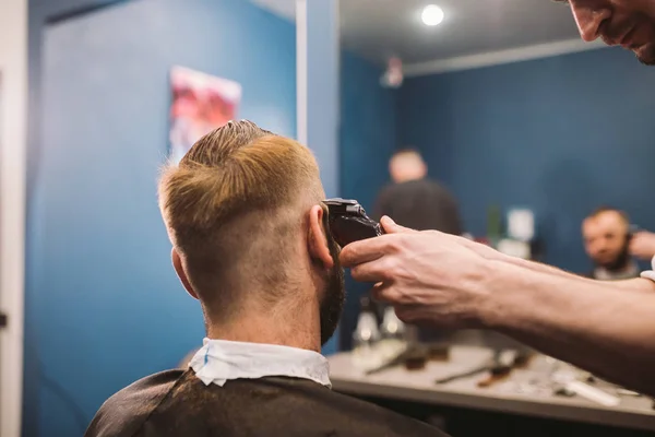 Close-up shot van de man krijgen van trendy kapsel bij de kapper. Mannelijke Haarstylist portie klant, waardoor kapsel met machine en kam — Stockfoto