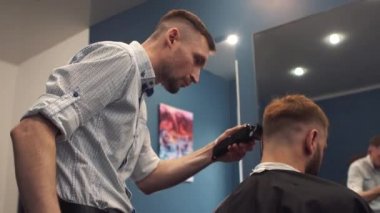 Adam son moda saç kesimi kuaför dükkanında elde kadeh kapatın. Erkek kuaförü hizmet istemci, makine ve tarak kullanarak saç kesimi yapma