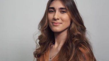 beyaz zemin üzerinde uzun kıvırcık saçlı güzel kadın portresi. Makyaj, moda, güzellik