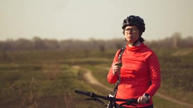 Atletik Beyaz kadın doğada dağ bisikleti üzerinde protein bar yolculuğu yiyor. Beslenme çubuğu Niyat ederken kask dinlenme genç sportif kadın atlet. Fitness kadın açık enerji snack yeme