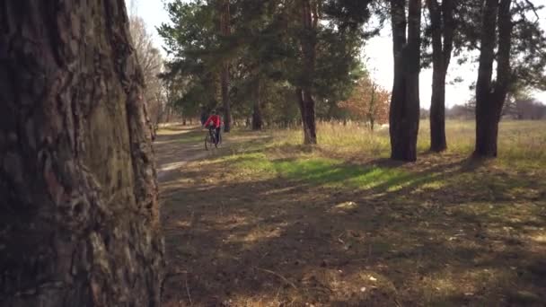 Caucasiano esporte ciclista mulher esporte off-road bike park perto da árvore. Uma atleta feminina em roupas esportivas e um capacete e uma mochila preta parar de treinar em mountain bike — Vídeo de Stock