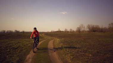 Atletik Beyaz kadın doğada dağ bisikleti üzerinde protein bar yolculuğu yiyor. Beslenme çubuğu Niyat ederken kask dinlenme genç sportif kadın atlet. Fitness kadın açık enerji snack yeme