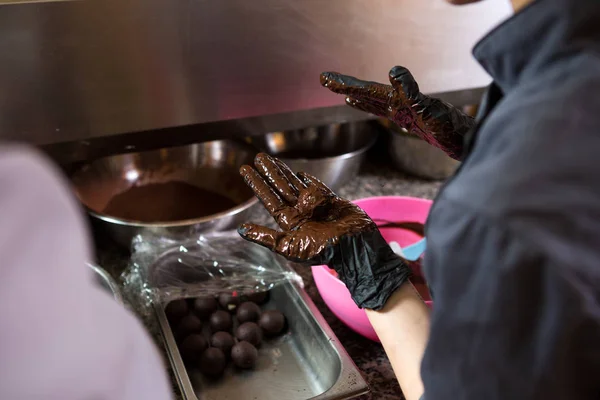 Tematicky se vaří lanýže. Blízkou rukou mladá Kavkazská žena a muž vaří s tetováním a v uniformním přípravě, a tak si vezměte sladkost koláče. Cukrár pokrývá malinový puer — Stock fotografie