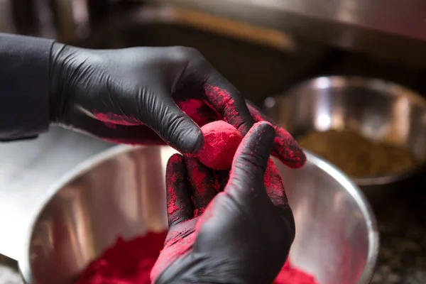 Thema Kochen Pralinen Trüffel. Nahaufnahme Hand junge kaukasische Frau und Mann Koch mit Tätowierung und in Uniform bereitet, macht runde Balltake die Süße des Kuchens. Konditor deckt Himbeerpuffer zu — Stockfoto