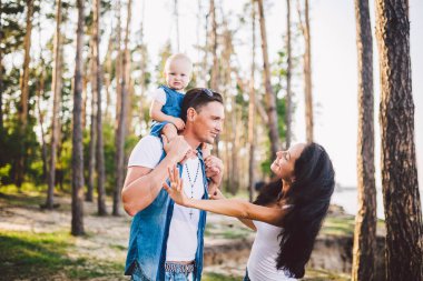 Aile anne, baba ve kızı oturur baba omuzlarında ve veliler ormandaki niteliğine yaz gün batımında öpücük
