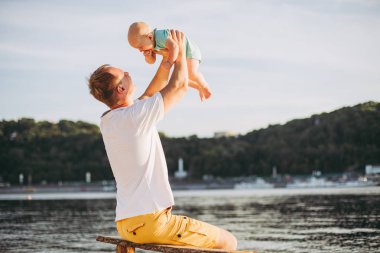 Konu rekreasyon baba ve küçük oğlu. Genç beyaz baba, Kiev kasabasına bakan ve Dinyeper nehrini tutan ahşap bankta oturur, bankalar daki kumlu plajda yeni yürümeye başlayan bir bebeğe sarılır.