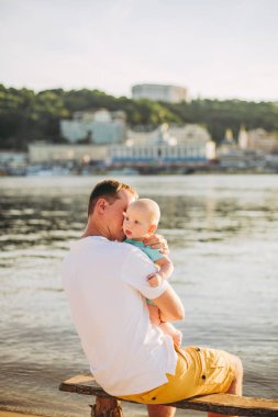 Konu rekreasyon baba ve küçük oğlu. Genç beyaz baba, Kiev kasabasına bakan ve Dinyeper nehrini tutan ahşap bankta oturur, bankalar daki kumlu plajda yeni yürümeye başlayan bir bebeğe sarılır.