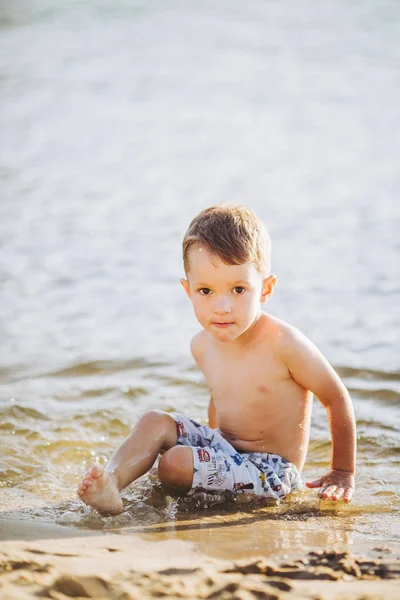 Thema ist die Sommerzeit und die Ruhe am Wasser. kleiner fröhlicher kaukasischer lustiger Junge spielt und genießt im Fluss. das Kind ruht sich aus und schwimmt im Teich — Stockfoto