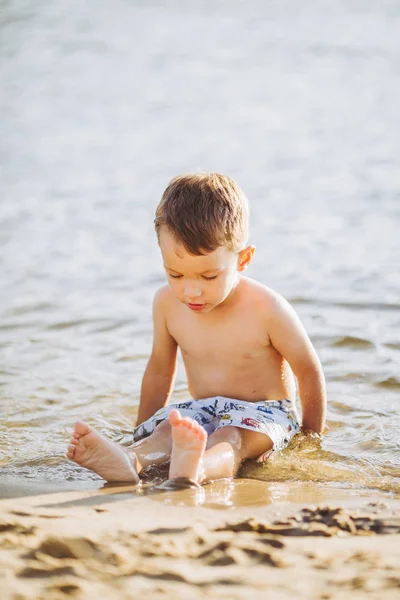 Thema ist die Sommerzeit und die Ruhe am Wasser. kleiner fröhlicher kaukasischer lustiger Junge spielt und genießt im Fluss. das Kind ruht sich aus und schwimmt im Teich — Stockfoto