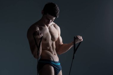Kas Fitness genç erkek antika mükemmel kaslar altı paketleri ABS ve çıplak göğüs. Stüdyodan karanlık bir arka plana karşı streç elastik ile vücut geliştirmeci Model trenler. Egzersiz eğitim spor salonu