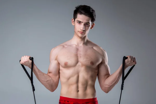 Muskularny fitness młody męski zabytkowe doskonały mięśnie sześć opakowania z ABS i nagi skrzynia. Kulturysta model pociągów z rozciągania elastyczny na ciemnym tle w studiu. Trening treningowy siłownia — Zdjęcie stockowe