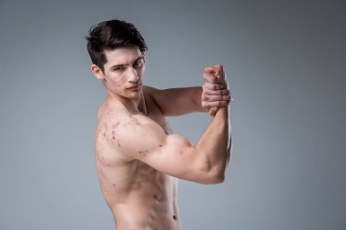 Gri arka planda stüdyo portre Genç beyaz adam poz. Ergenlik teması, problem cilt, Genç akne. Kafkas atlet Fitness. Alerji spor beslenme, takviyeleri steroidler